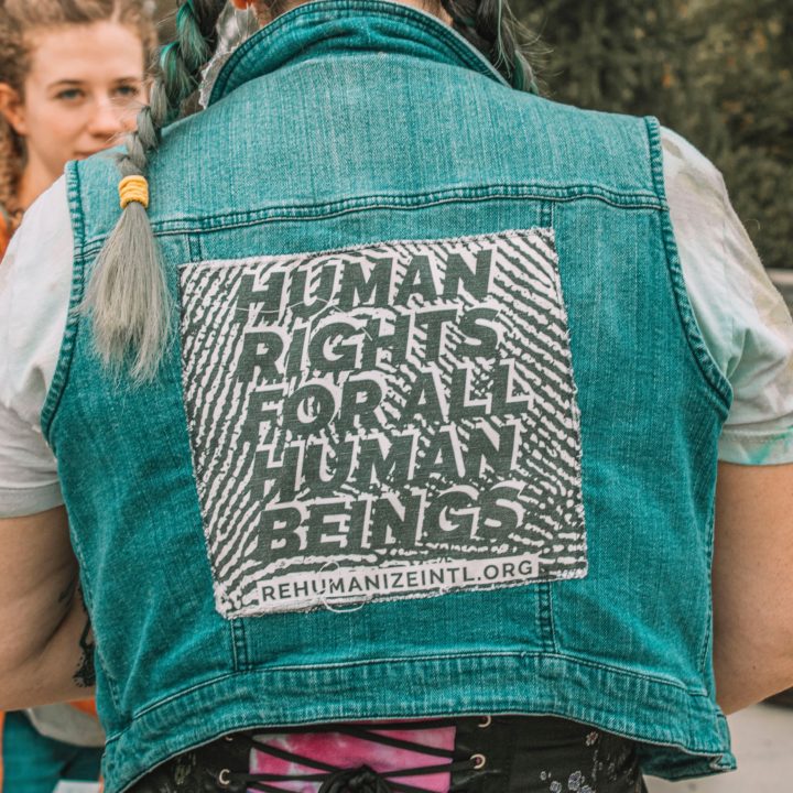 Person wearing green vest that says Human Rights for all Human Beings